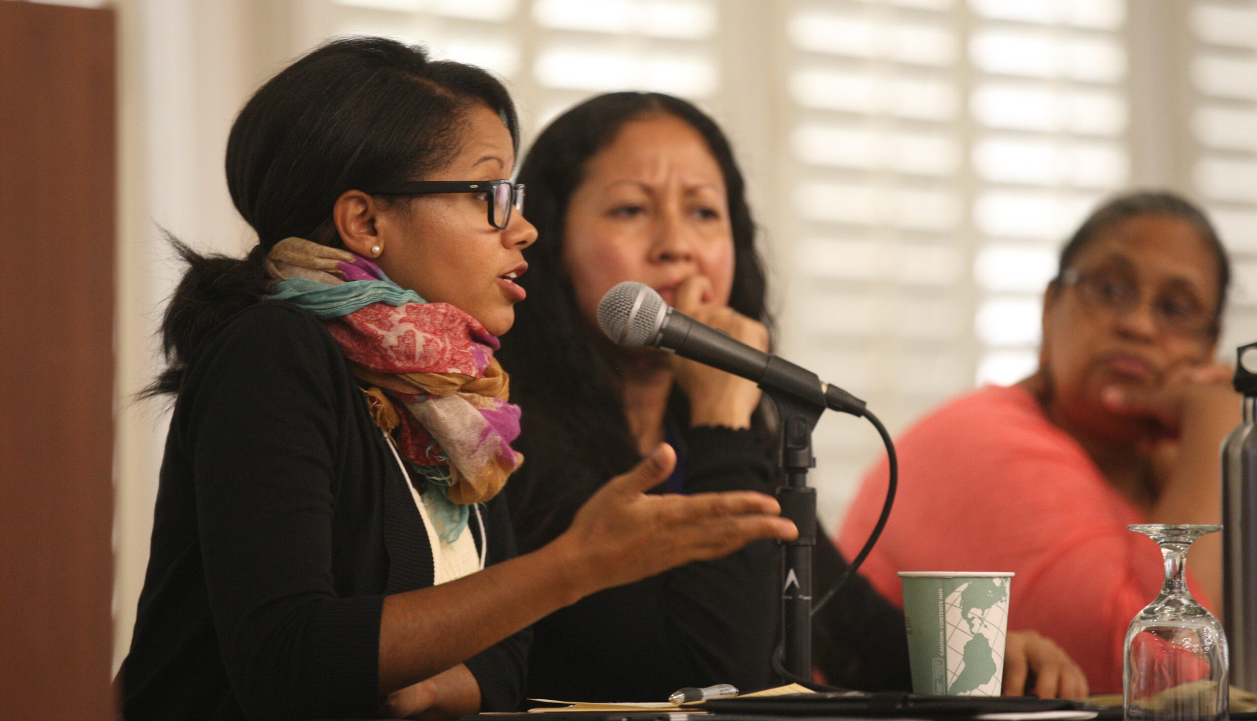 woman speaking into a microphone as a part of a panel at a conference