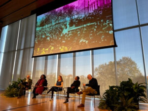 Five speakers sitting on a stage at an event